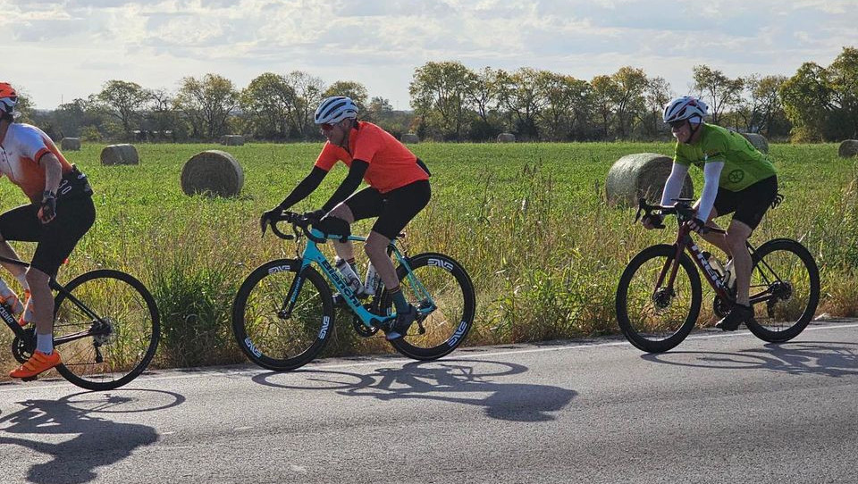 bikers riding along rural street with hay bales in the background