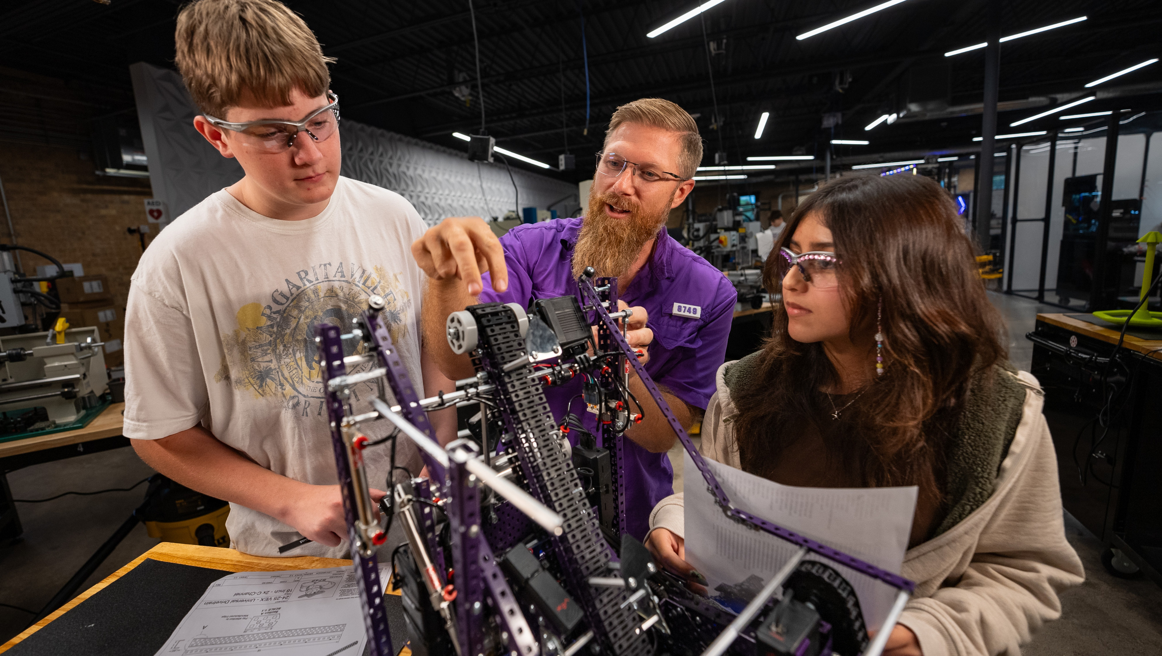 robotics students with teacher looking at robot