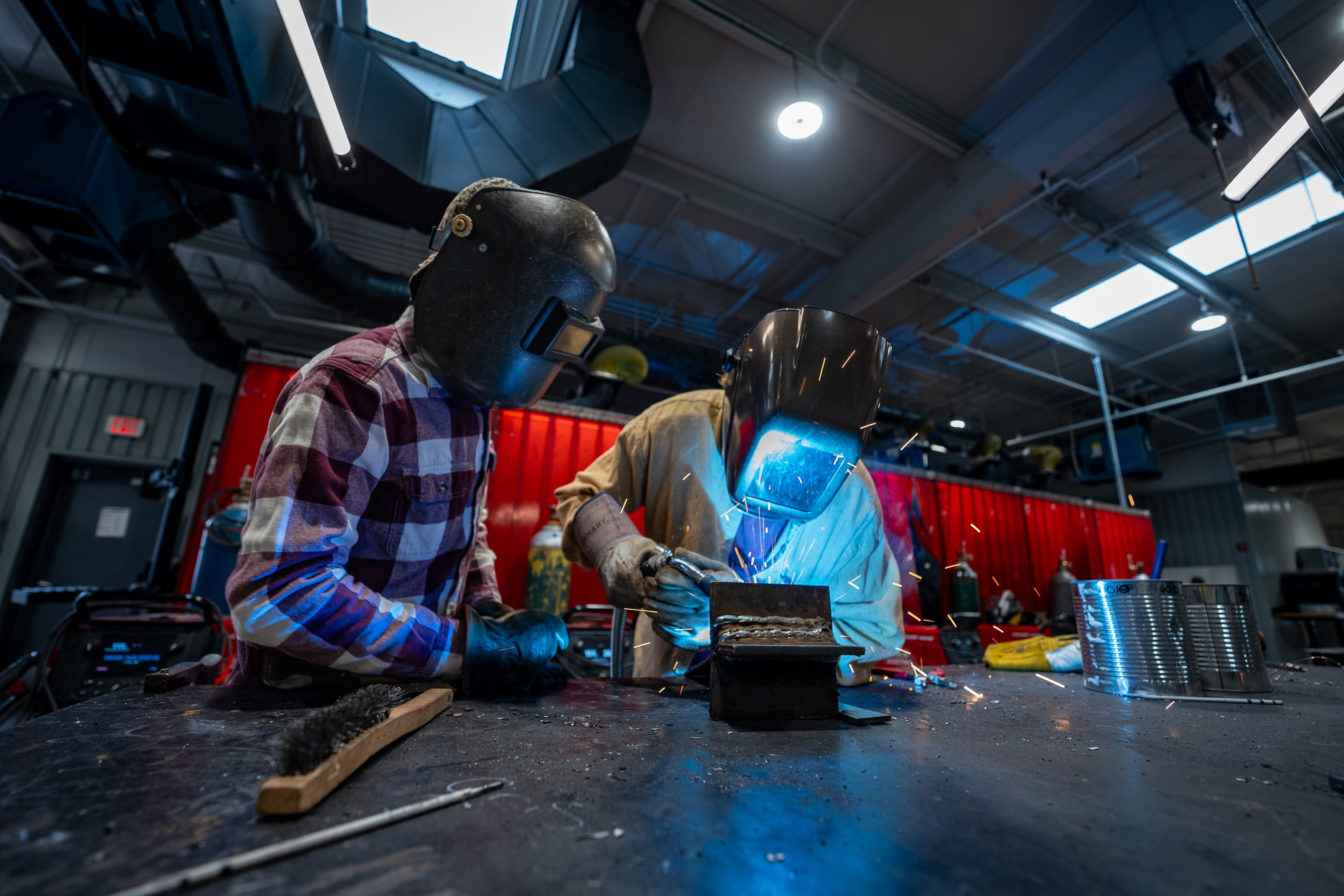 Men welding metal together while wearing saftey gear
