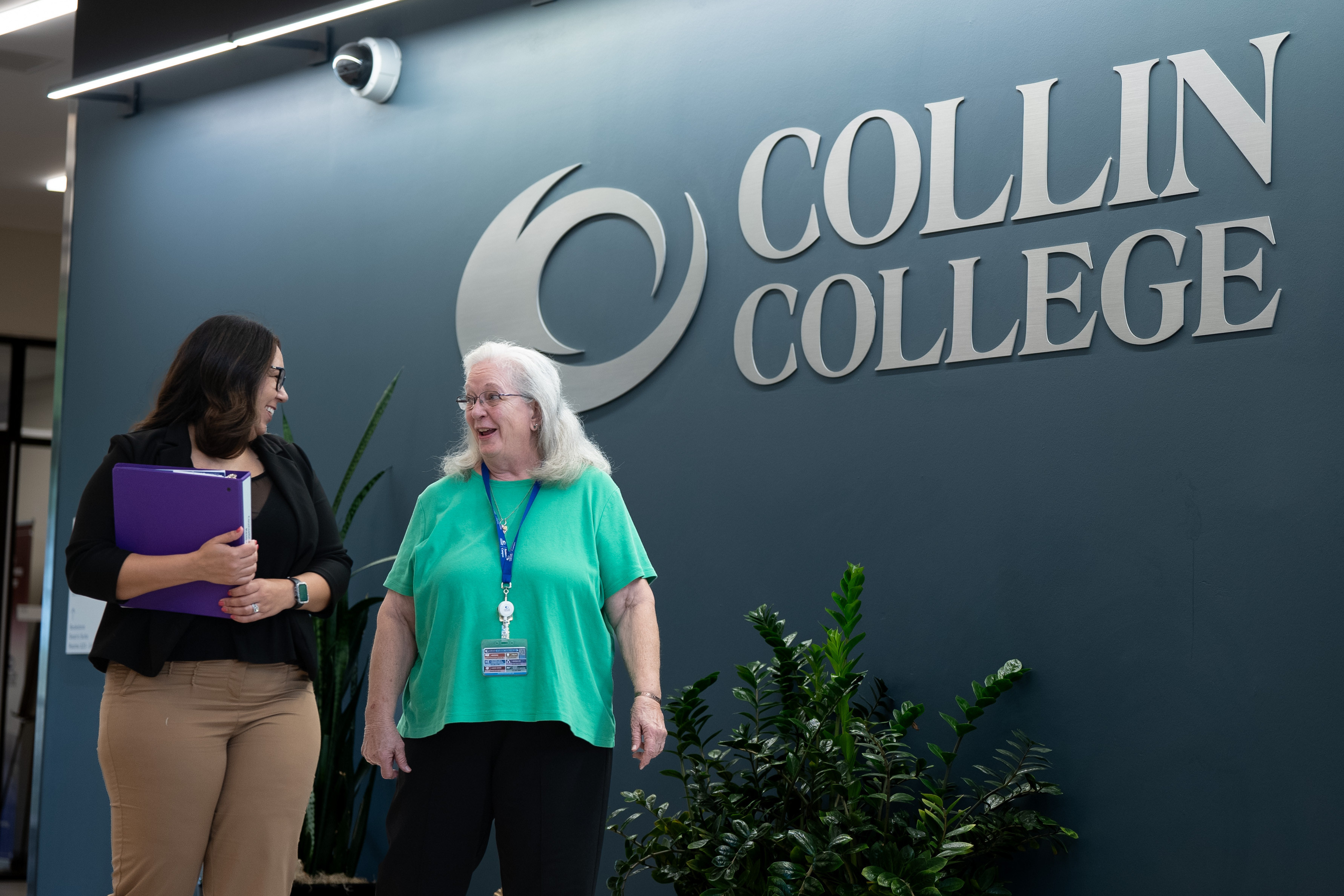Collin College staff talking with college sign in the background